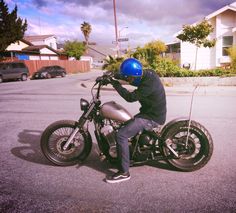 a man sitting on top of a motorcycle in the middle of a parking lot next to houses