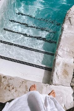 a person laying in front of a swimming pool with their feet up on the edge