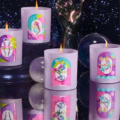 several candles with unicorns on them sitting in front of a vase and some balloons