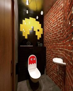 a bathroom with a toilet, sink and pacman sticker on the wall