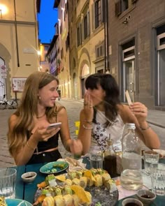 two women sitting at a table with food in front of them