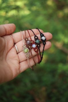 a person is holding three different bracelets in their hand, one with beads and the other with stones