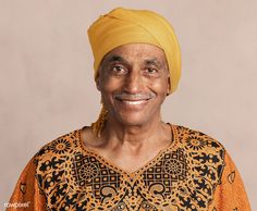 a man with a yellow turban smiles at the camera while standing in front of a gray background