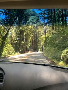 a car driving down a road surrounded by trees