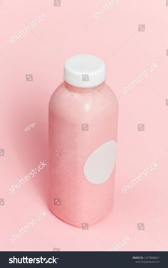 a pink plastic bottle with white polka dots on the top and bottom, against a pink background