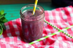 a mason jar filled with blueberry smoothie on top of a red and white checkered table cloth