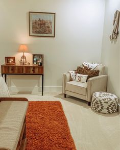 a living room with a couch, chair and ottoman in the corner next to a dresser