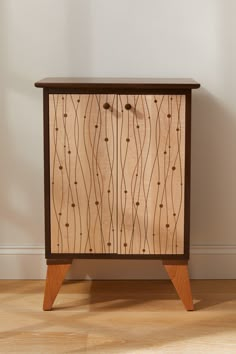 a wooden cabinet sitting on top of a hard wood floor next to a white wall