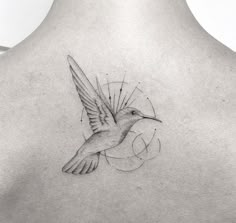 the back of a woman's neck with a bird tattoo on it