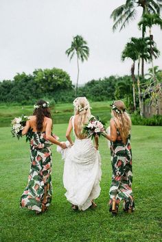 three bridesmaids walking in the grass holding hands