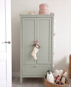 a green armoire sitting next to a basket filled with christmas stockings and other decorations