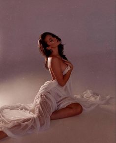 a woman in a white dress sitting on the floor