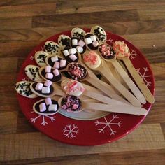 a red plate topped with lots of cupcakes and marshmallows on sticks