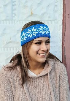 a woman wearing a blue headband with white flowers on it and smiling at the camera