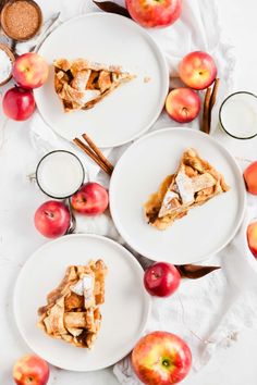 three plates with slices of apple pie on them next to some apples and cinnamon sticks