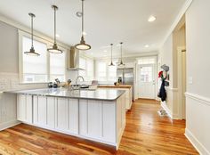 a large kitchen with an island in the middle and wood flooring on the other side