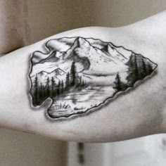 a man's arm with a mountain and forest tattoo on the left side of his arm