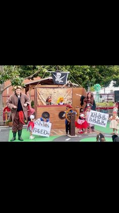 some people are standing in front of a pirate ship with signs on the side walk