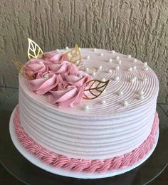 a white cake with pink frosting and gold decorations