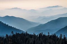 the mountains are covered in fog and low lying clouds as they rise into the distance