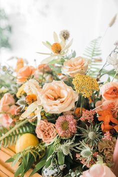 an arrangement of flowers and greenery on a table