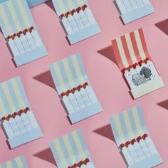 several small candy bags are lined up on a pink surface with red and blue pins