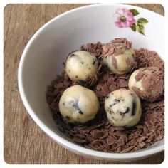 four chocolate desserts in a white bowl on a wooden table with pink flower decoration