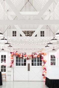 an indoor event with balloons and lights hanging from the ceiling