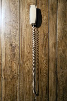 an old fashioned phone is hanging on the wood paneled wall in a room with wooden flooring