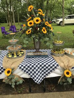 a table topped with sunflowers and cupcakes on top of a checkered cloth