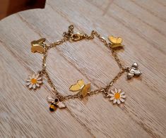 A gold colored charm bracelet made with enamel bee and flower charms, and metal butterfly charms. Made with iron, nickel-free hardware. Adjustable. Charm Bracelet Aesthetic, Bracelet Breloques, Bracelet Aesthetic, Bee And Flower, Aesthetic Flower, Metal Butterfly, Bee Charms, Bracelet Charm, Butterfly Charm