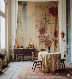 a table and chairs in front of a wall with flowers on the curtained window