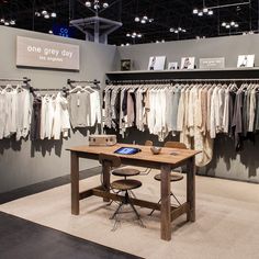 a table with two chairs in front of it and some shirts hanging on the wall