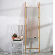 a white chair sitting next to a tall wooden rack with a blanket on it's back