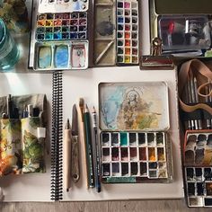 an assortment of art supplies including watercolors, paintbrushes and pencils