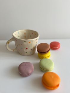 there is a cup and some macaroons on the table next to each other