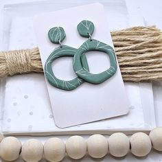 a pair of green earrings sitting on top of a piece of paper next to some wood beads