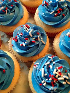 cupcakes with blue frosting and sprinkles are arranged on a plate