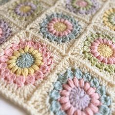 a crocheted granny blanket with flowers on the top and bottom, in pastel colors