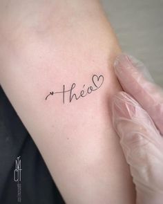 a person with a tattoo on their arm that says,'thea'in cursive writing