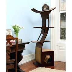 a cat sitting on top of a scratching tower in a living room next to a table