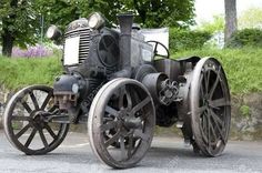 an old fashioned tractor is parked on the side of the road