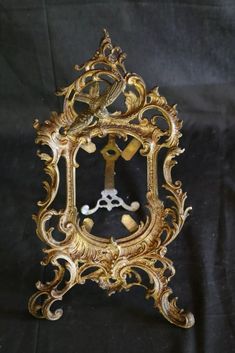 an ornate gold clock with a bird on it's face is shown in front of a black background