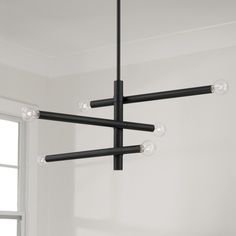 a black chandelier hanging from the ceiling in a room with white walls and windows