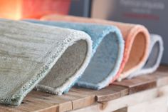 three different colored rugs sitting on top of a wooden shelf next to each other