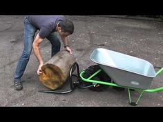 a man pushing a wheelbarrow next to a log