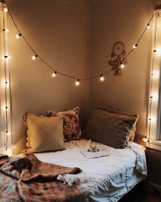 a bed with some lights on the wall above it and a blanket in front of it