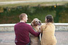 a man and woman sitting on the ground with their dog