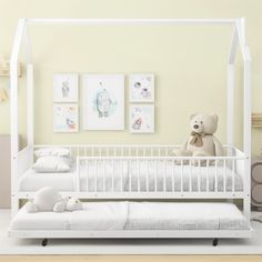 a teddy bear sitting on top of a white crib next to a baby's bed