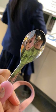 a person holding a spoon with two pictures on it and a pink rubber band around the handle